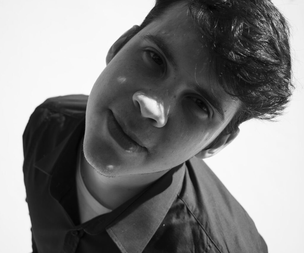 Ritratto in bianco e nero del giovane proprietario del sito BonDesign con la testa inclinata mentre accenna un sorriso